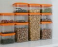 Various nuts and grains stored in transparent plastic containers with orange lids, organized neatly.
